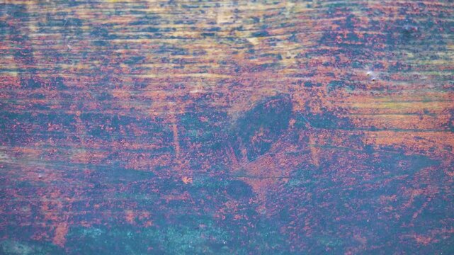 Drippings, drip. The falling drops break on a board made of old wood and form water craters and splashes.