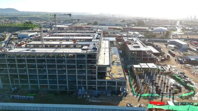 Distant aerial view of hospital construction site with mountain backdrop Keywords extra: mountains, background, empty lot, vacant land, wide angle, skyline