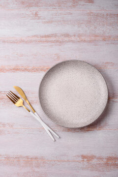 An empty round ceramic plate on a dark, textured white background. An empty round plate