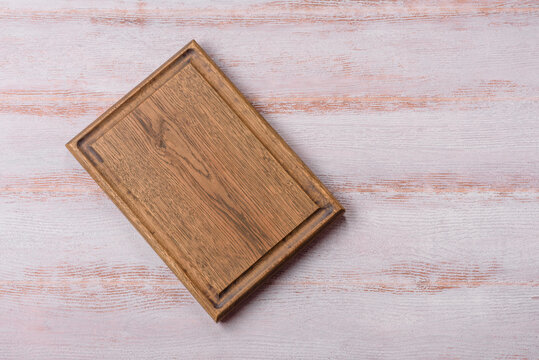 A square wooden cutting board for home food preparation. A wooden cutting board