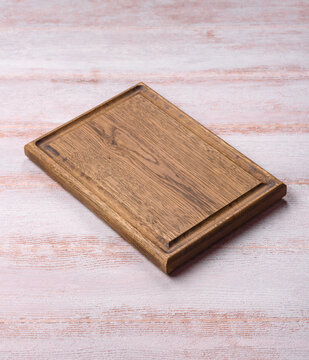A square wooden cutting board for home food preparation. A wooden cutting board