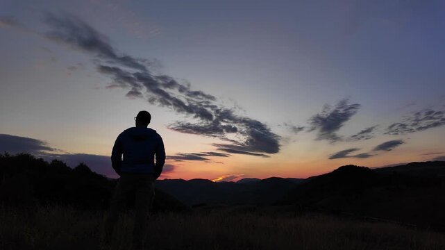 Silhouette of a man looking at the mountain sunset.