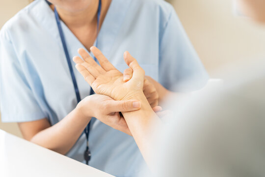 Close up of a physical therapist massaging and examining a patient hand for wrist and trigger fingers rehabilitation, carpal tunnel syndrome and office syndrome occupational therapy medical concept.