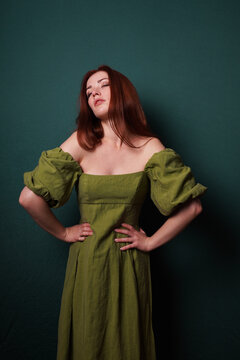 woman in vintage dress striking expressive model pose with hands on hips eyes closed and head tilted back