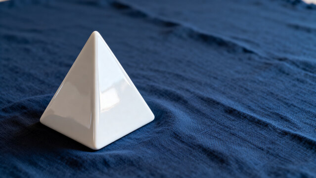 equilateral. Single white equilateral triangle object on deep blue linen, calm still life for editorial concept, lifestyle magazines.