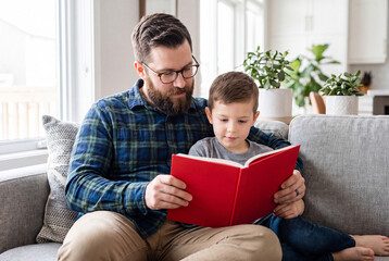 Fototapeta premium Happy Father Reading Storybook to His Young Son at Home Family Bonding and Early Childhood Education