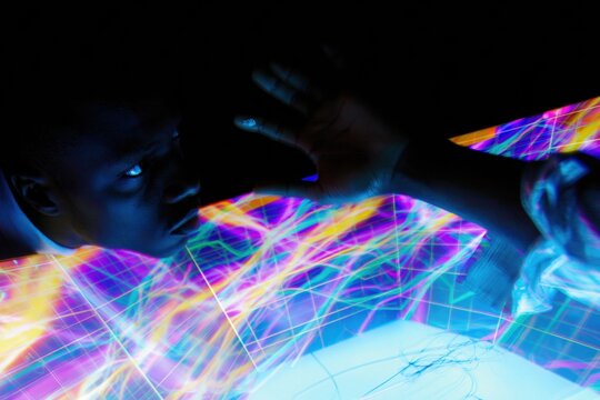 Focused man analyzing glowing digital data graphs on an illuminated screen at night for big data and cybersecurity analytics