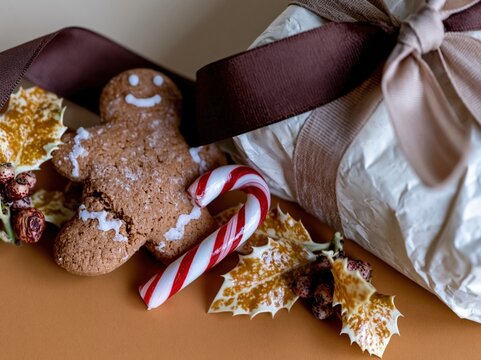 Gingerbread man cookie and wrapped gift box with silk ribbon in a cozy Christmas flat lay for holiday greetings and festive seasonal promotions