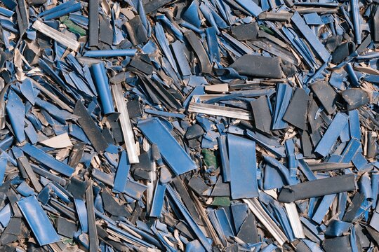 Shredded plastic flakes in a dense heap showing scuffed textures and sharp edges for recycling and circular economy reporting