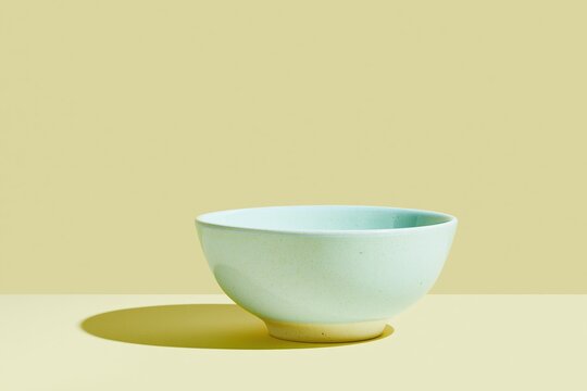 Minimalist empty sage green ceramic bowl on a light khaki surface, featuring a smooth glazed finish and calm mood for food presentation mockups
