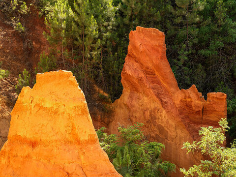Two rocky outcrops, one of yellow ochre and one of red ochre, rise up from the vegetation