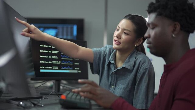 Two diverse programmers working together on a coding project in a modern office.
