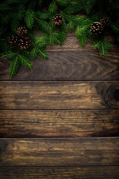 Christmas background with fir branches and pine cones on rustic wooden boards, christmas decoration