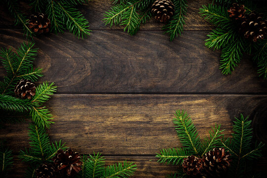 Christmas background with fir branches and pine cones on rustic wooden boards, christmas decoration