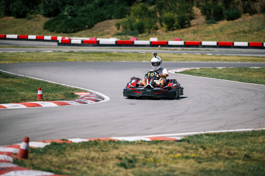Teenage boy racing a go-kart and leaning into a turn outdoors