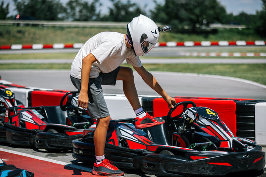 Teenage boy stepping into a go-kart on an outdoor racing track
