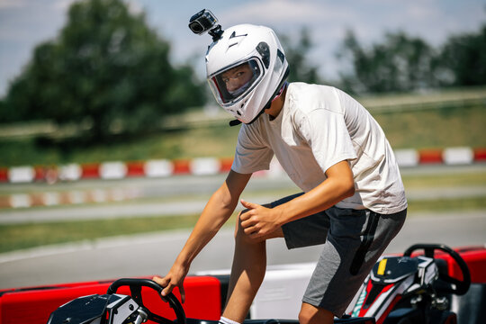 Young driver giving thumbs up gesture while entering a go-kart outdoors