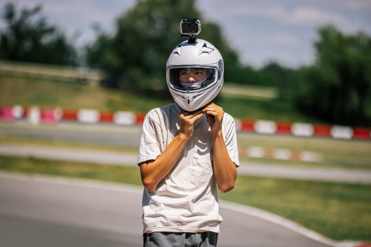 Teenager taking off his helmet trackside after a go-kart race