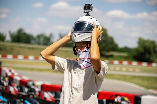 Happy teenager taking off his helmet after an outdoor karting session