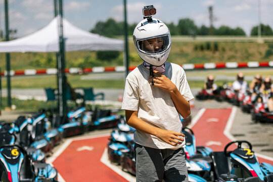 Teenage boy wearing helmet while preparing for go-kart racing on an outdoor track