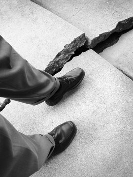Business Man Person Walking with Dress Shoes Next to Broken Cracked Sidewalk Avoiding Danger
