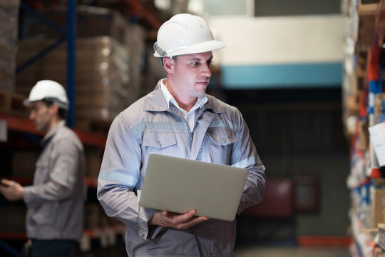 Male warehouse worker manage inventory, process incoming and outgoing stock, and fulfill orders inside a storage or distribution facility