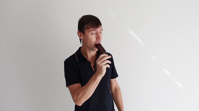 homem comendo picol&eacute; saboroso de chocolate 