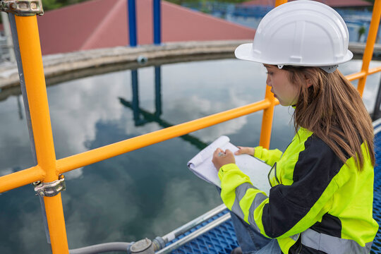 Female engineer recording inspection data at a water treatment plant. Concept of water quality, utility operations, environmental engineering, infrastructure and safety.