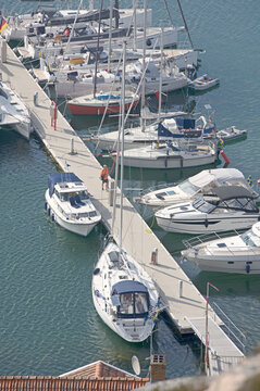 Boats moored in rows at a marina seen from a clifftop