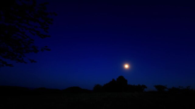 Moon on a twilight sky with landscape mountain silhouettes.