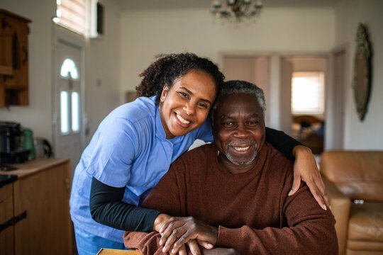 Smiling caregiver embracing senior man at home
