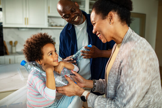 Smiling family recycling plastic bottles in home kitchen