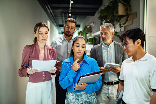 Diverse business team discussing project in office hallway
