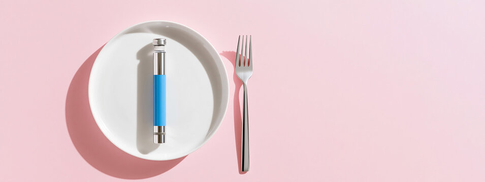 Weight Loss Injection Pen on White Plate with Fork Minimalist Diet Concept on Pink Background with Copy Space