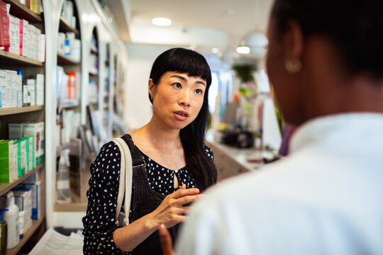 Woman consulting pharmacist about medication in pharmacy