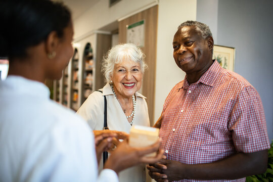 Senior couple consulting pharmacist at pharmacy counter