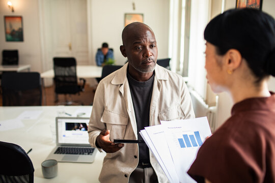 Business colleagues reviewing financial reports in open office