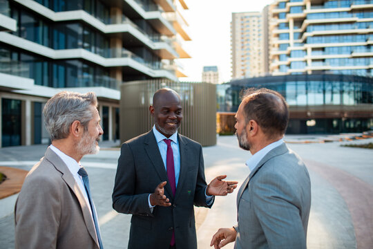 Three businessmen discussing outside modern office complex