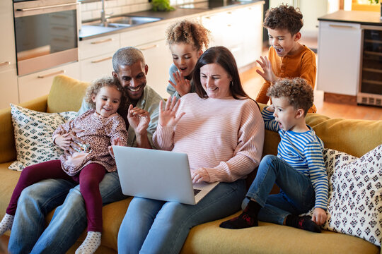 Parents and children waving on laptop video call at home