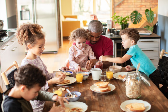 Father helping children eat breakfast at home