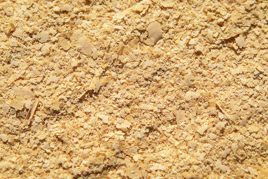 Close-up of nutritional yeast flakes texture, savory cheesy vegan seasoning and food ingredient background