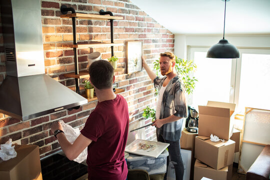 Two men decorating kitchen in new apartment with moving boxes