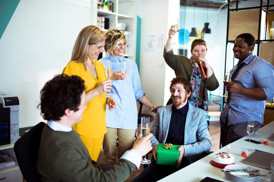 Coworkers celebrating an office birthday with cake and champagne