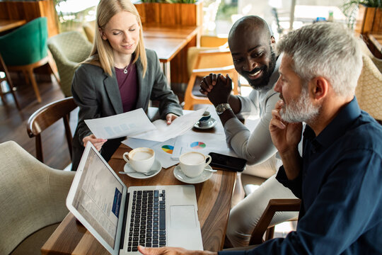 Three colleagues discussing financial reports in coffee shop
