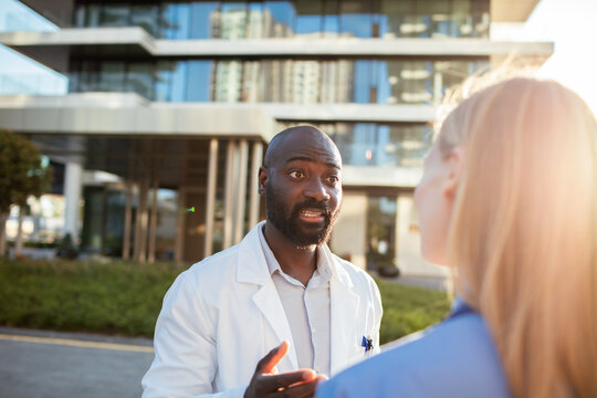 Doctor talking with colleague outside modern hospital