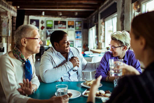 Diverse friends laughing over coffee at a cafe