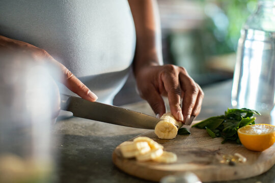Close-up of person slicing banana on cutting board in home kitchen