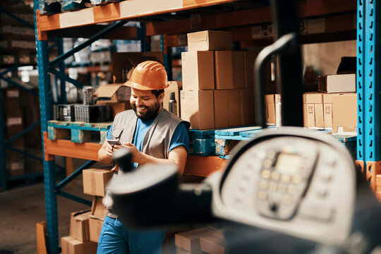 Smiling warehouse worker using smartphone in distribution center