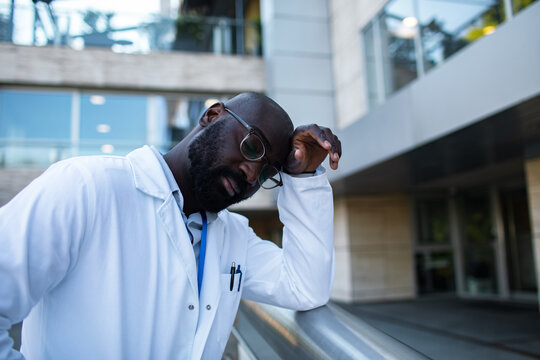 Exhausted doctor leaning on railing outside hospital