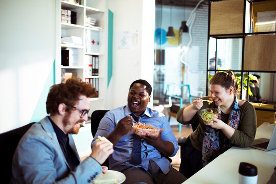 Coworkers enjoying lunch break together at modern office
